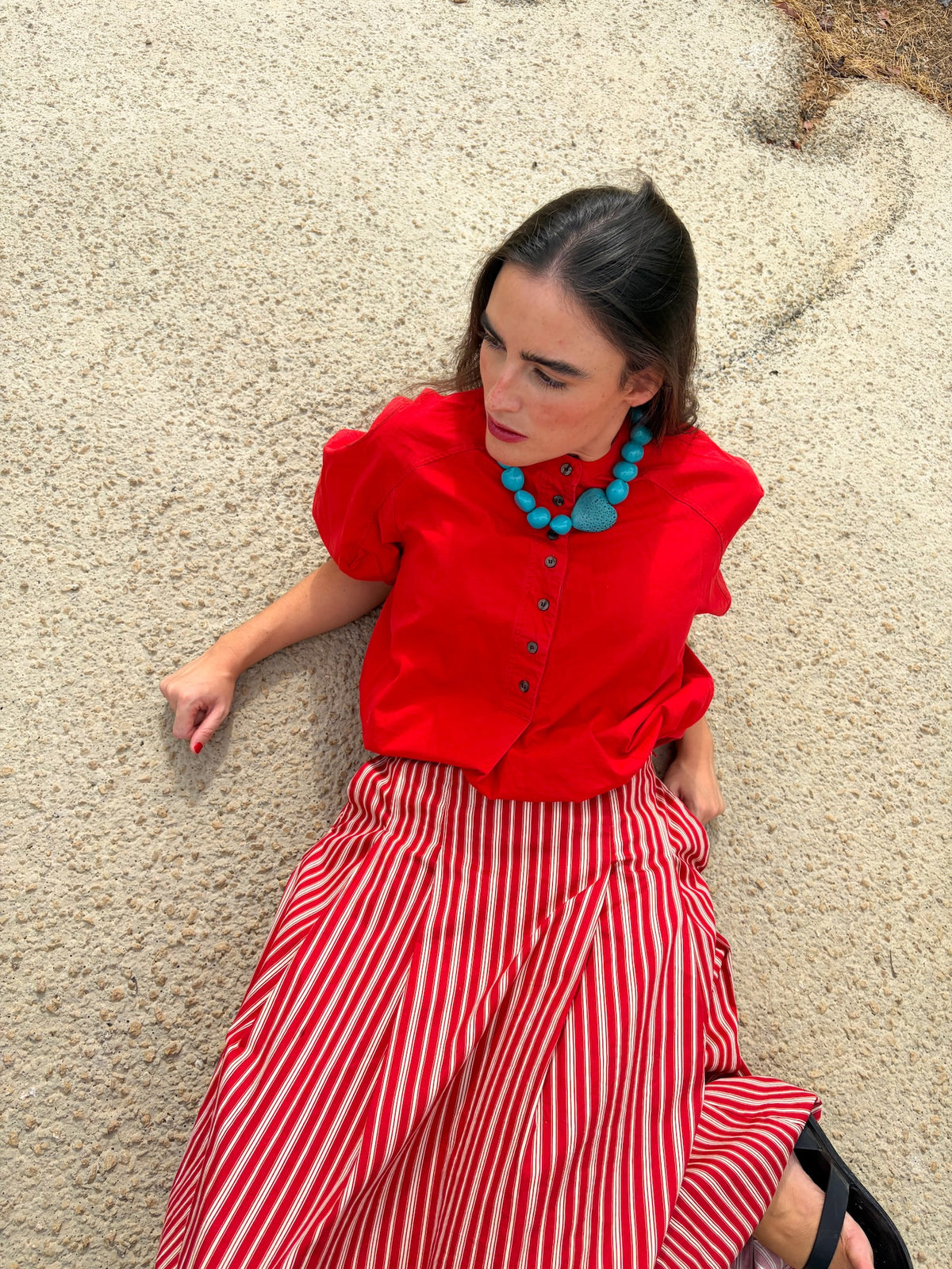 Collar de semillas de coco turquesa con corazón, puesto con blusa roja y falda de rayas | esdeinés