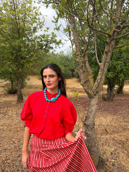 Collar turquesa con corazón grande puesto, look completo con falda de rayas | esdeinés